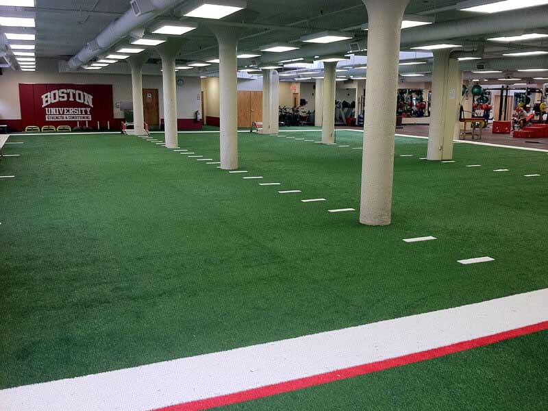 Indoor agility training turf at Boston University with line markers and BU colors