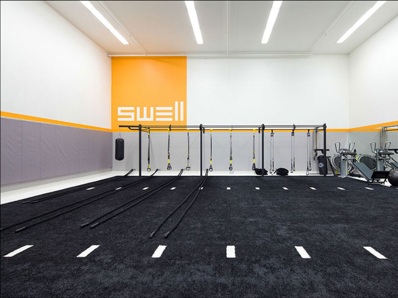 Swell indoor gym with black sports turf and resistance cords rack