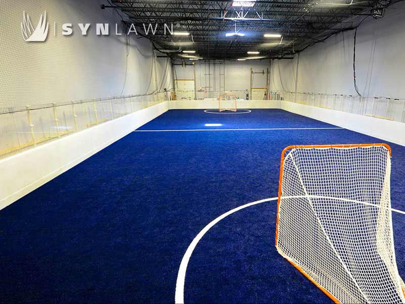 Blue field turf for indoor soccer or roller hockey room with white walls and exposed rafters