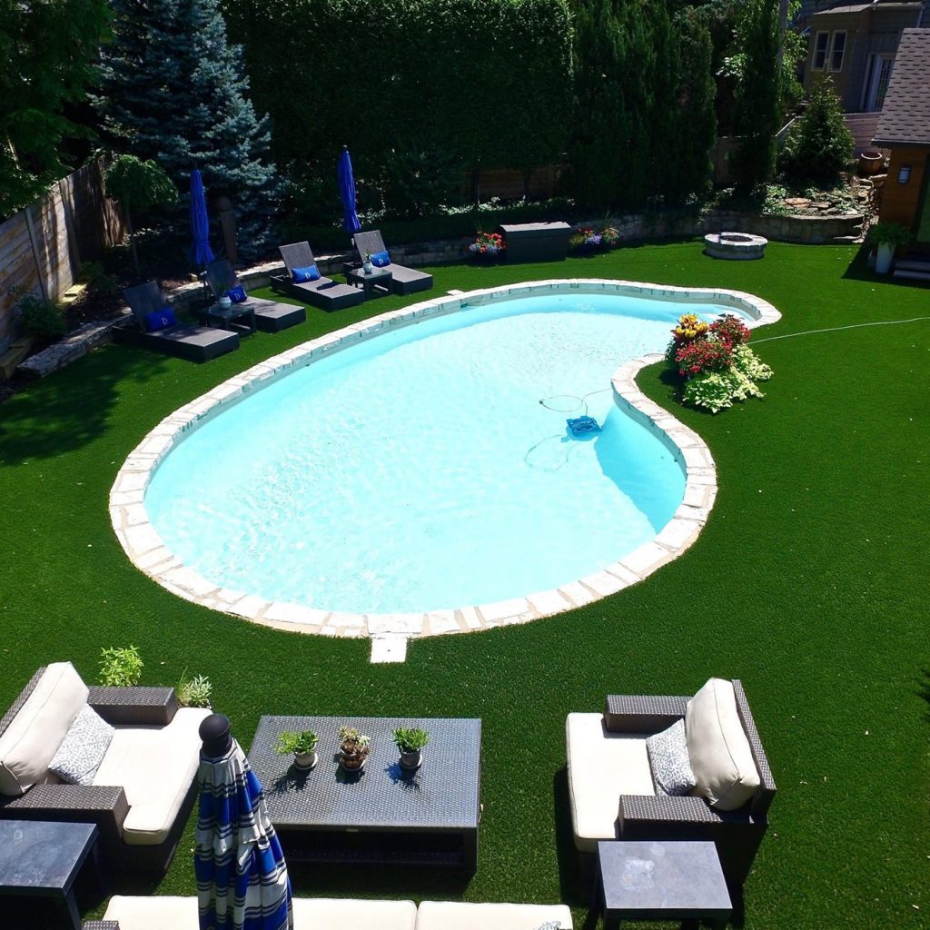 Artificial grass backyard with a pool and patio set. 