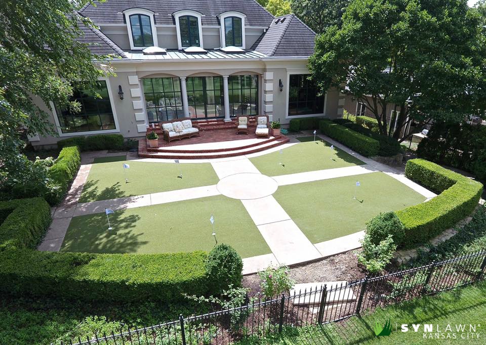 A Kansas City backyard with a synthetic grass lawn and a brick porch with seating.