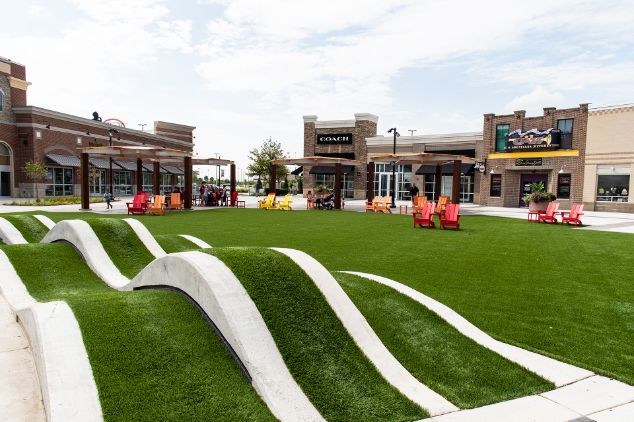 Artificial grass play and common area with businesses in front