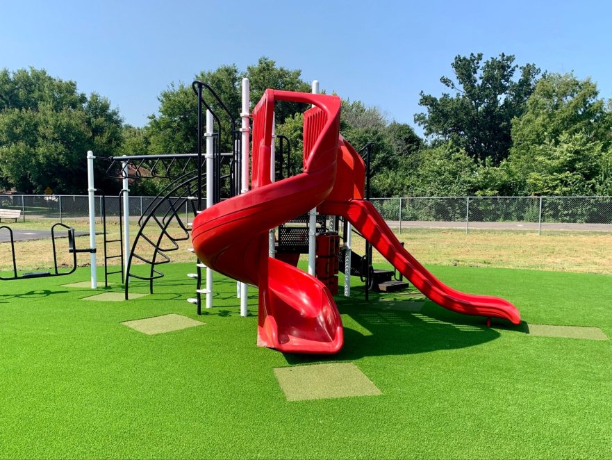 Red slide installed on artificial playground grass