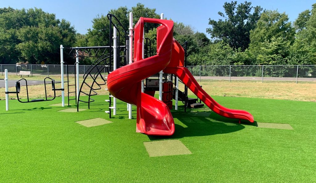 Red slide installed on artificial playground grass