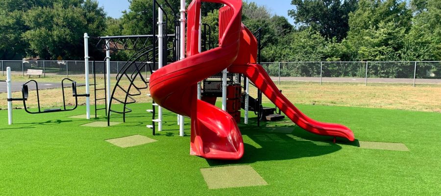 Red slide installed on artificial playground grass